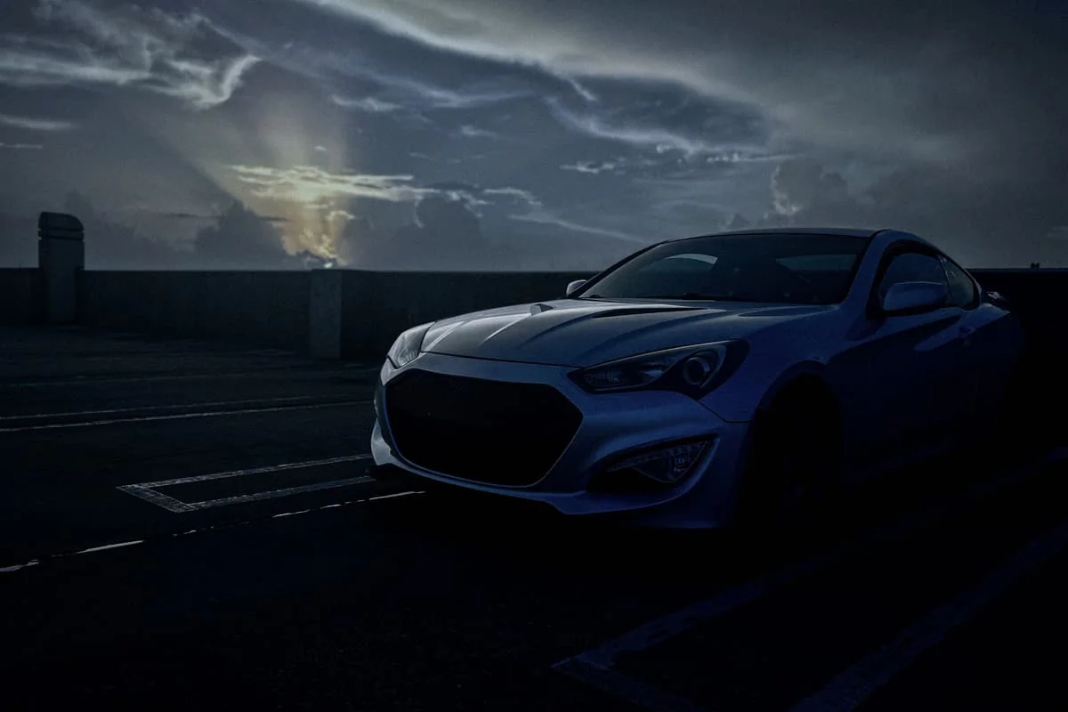 Silver Genesis Coupe beneath storm clouds